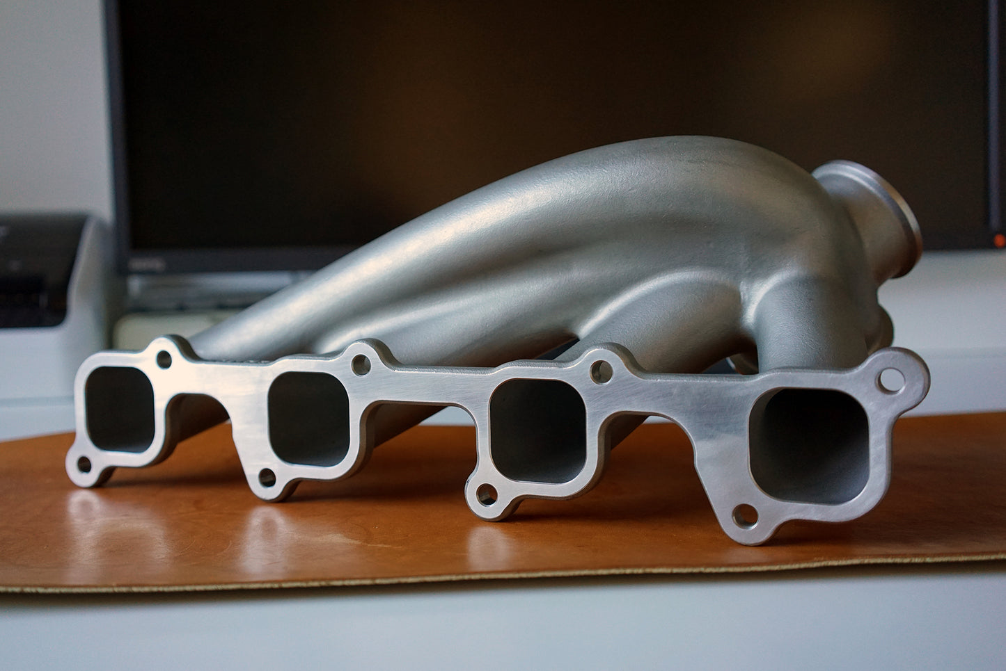 Cast 347 stainless Volvo 8-valve turbo manifold showing cylinder head flange and precision-machined mating surface