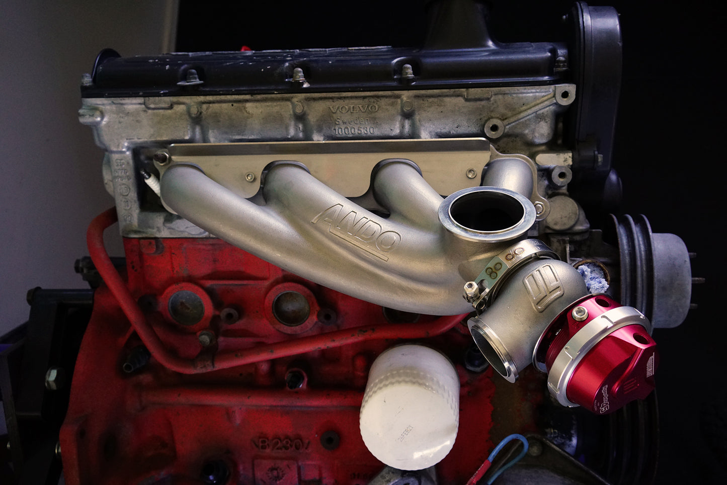 Side view of Ando Engineering Volvo 8-valve turbo manifold installed on B230 engine showing fitment around factory components
