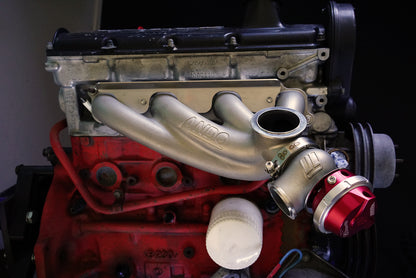 Side view of Ando Engineering Volvo 8-valve turbo manifold installed on B230 engine showing fitment around factory components
