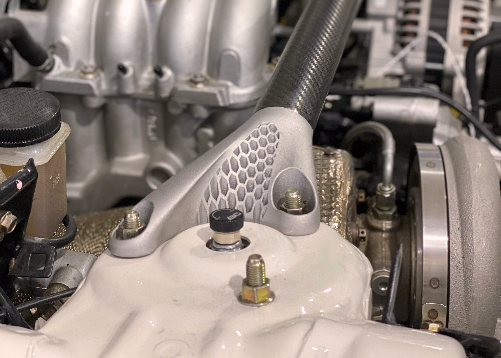 Carbon fibre RX7 strut brace with metal 3D printed aluminium mounts demonstrating additive manufacturing and component design